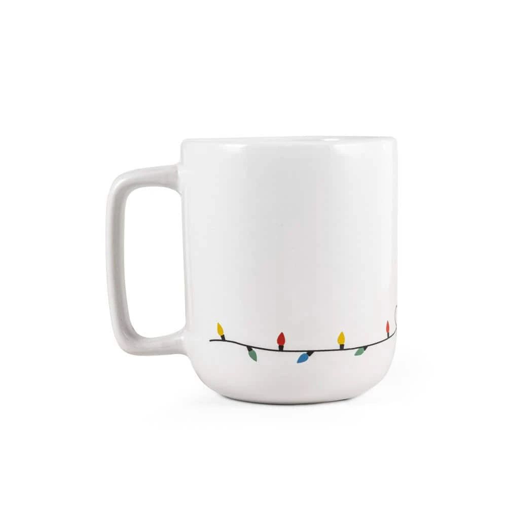 Vit julmugg med ren och julbelysning i färgglada ljus.