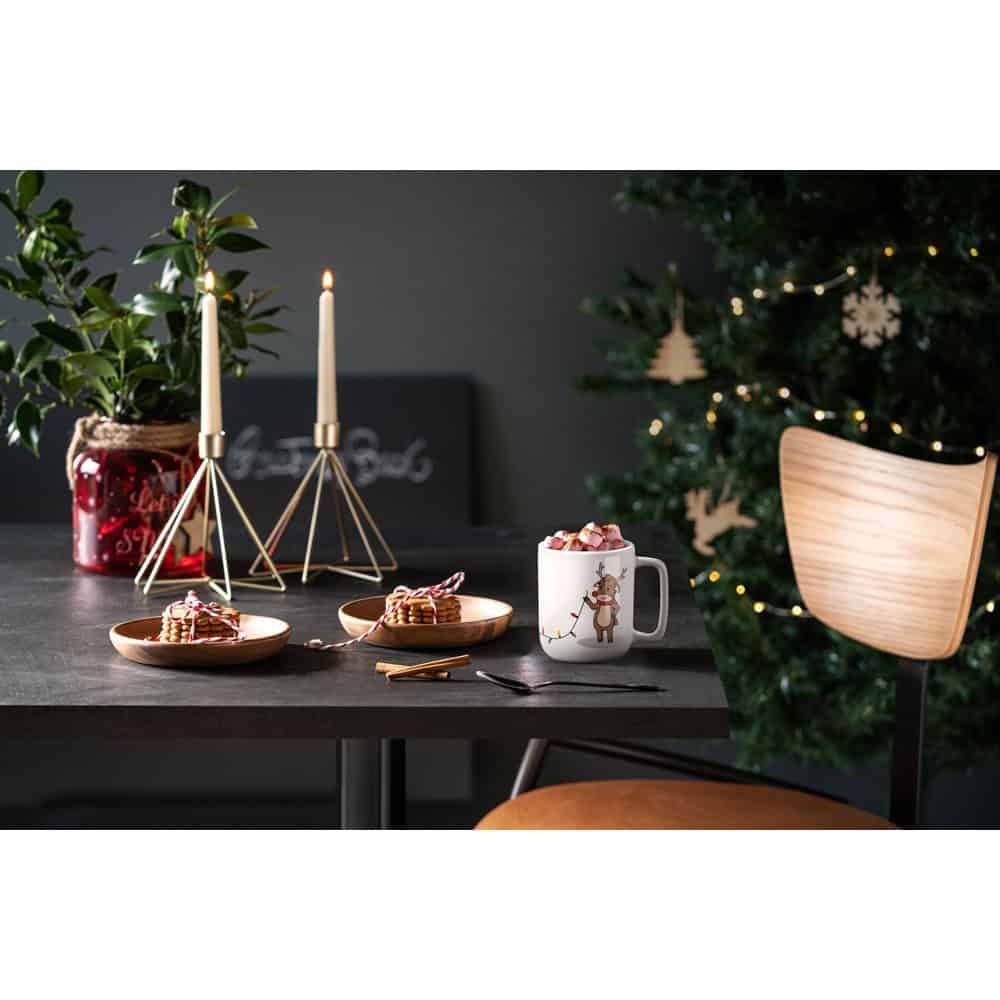 Reindeer mugg med jultryck, perfekt för julfika och fest. Decorativt julbord med ljus och gran i bak.