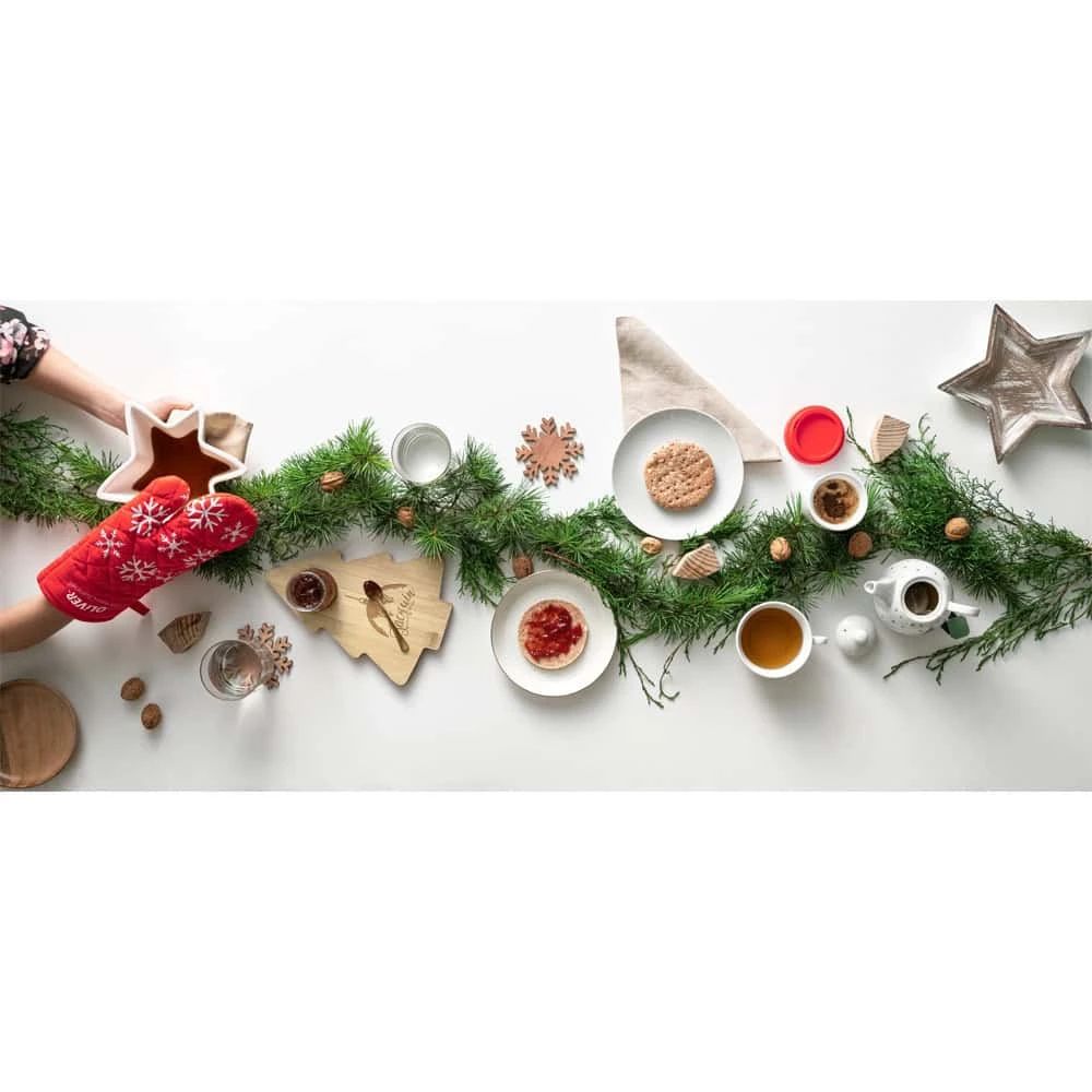 Julservis med granris och juldekorationer på ett vitt bord.