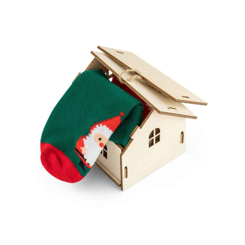 Julstrumpa i grönt och rött med tomtemotiv, placerad i ett trähus.